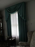 Teal window treatment on a single window with white sheer curtain visible behind it
