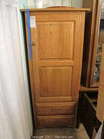 Front view of wood pantry cabinet with closed door and two bottom drawers