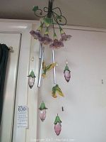 Full view of flower and bird wind chime with hanging metal tubes and ceramic floral pendants