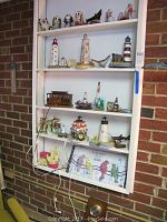 Shelf with five lighthouse lamps and various figurines arranged in groups, showing the full lot.