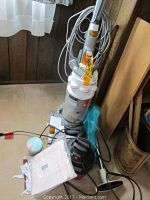 Full view of upright Dyson vacuum cleaner with accessories including hoses, brushes, and additional tools on the floor.