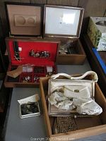 Wooden boxes and red velvet jewelry box containing purses and men's jewelry on tabletop