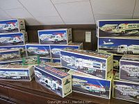 Wide display of 24 boxed Hess vehicles arranged on shelf; all in original packaging.