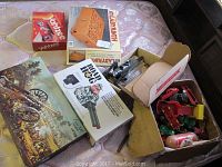 Photo showing board games Yahtzee, Labyrinth, Big Bang Cannon and 18th century cannon game box. Part of a box of toys visible to side.
