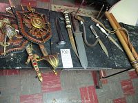 Full overview of lot: two plaques with mounted swords, two decorative sabers, decorative dagger, combat and fixed-blade knives
