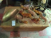 Top view of wood trunk with nine deer figurines, brass bowl, and scale with decorative hooks