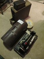 Vintage black Singer electric sewing machine Model 66-16 with attached electric motor, brown metal carrying case, wooden box of accessories, and round metal tin on carpet.