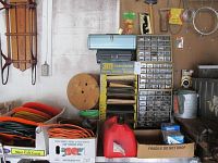 Overview of tools and hardware: extension cords, gas cans, bolt organizer, vintage sled, metal toolboxes.
