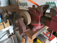 Photo showing red Simplex Utility 16800 table vise mounted on wood, grinding wheel next to it, with some rust and wear visible.