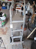 Front view of the metal furniture dolly showing the handle, construction, and dealer's logo.