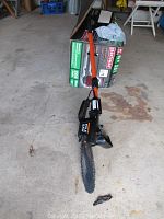 Remington pole saw with orange pole and chain blade laying on concrete floor, original box in background.