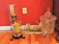 Overall lot including glass beverage dispenser, hurricane candle holder, and porcelain figurine sculpture
