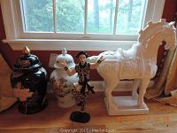 Photo showing the horse statue, two ginger jars and the jester figurine positioned on the floor in front of a window.