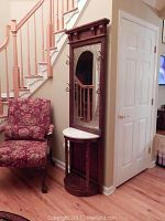 Full view of vintage wooden hall tree with marble moon-shaped table top and large beveled mirror showing overall design and condition.