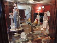 Overview of glass display cabinet showing all lot items including figurines, rooster and glass rose stem