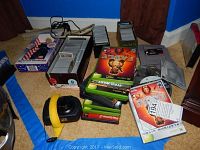 Photo showing grouped video games for Xbox, PlayStation, Nintendo and several Magic the Gathering card boxes and loose cards along with joystick controller.