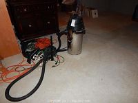 Shop-vac vacuum in room with black hose and orange power extension cords around it.