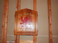 Closed wooden cabinet with 'The Red Lion Ale & Spirits' logo on the front displaying a red lion graphic, the cabinet is rectangular with a natural wood finish.