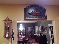 Wide shot showing wooden wall clock at left and Titanic wall art plaque above opening
