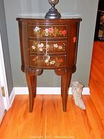 Front view of dark wooden accent table with three drawers featuring hand painted floral motifs. Table height approximately 35 inches.
