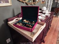 Open maroon flatware case showing gold tone cutlery inside, set for 8 people, includes forks, spoons, and knives.