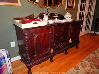 Front and side view of the wooden buffet showing 3 drawers in the center and 2 cabinets on each side. Ornate carving details on the wood and claw foot legs visible.