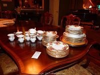 Full spread of china service on dining table showing stacks of plates, cups, saucers and charger plates