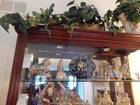Display cabinet shelf with assorted porcelain figurines including carousel horse and princess figures