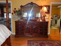 Front view of wooden dresser with attached mirror and decorative items on top