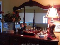View of the wooden dresser with ornate mirror, lamp, various perfume containers, tray, and floral arrangement in crystal vase.