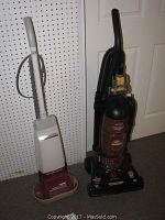 Two upright cleaning appliances side by side on carpet, Hoover shampoo polisher on left and Bissell Powerforce vacuum on right.