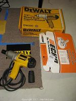 DeWalt DW290 1/2 inch heavy duty impact wrench, its original box, one impact socket, and Echo trimmer blade kit box arranged on a surface.