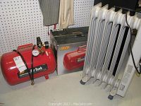 Side view of MVP red 5-gallon air tank next to its original box and white oil-filled radiator space heater