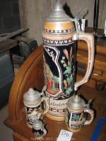 Group shot of four German beer steins in varied sizes on wooden surface