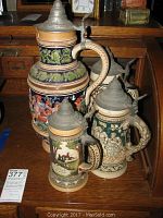 Three German steins arranged on wooden surface, showing overall lot