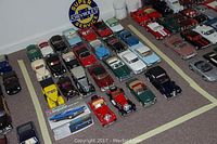 Overview of taped area showing approximately 22 die-cast model cars and one Impala kit box