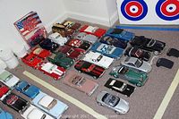 Overview of approximately 20 die-cast cars arranged on carpet