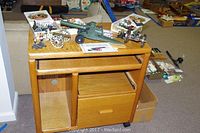 Wooden computer stand with multiple metal and plastic cannons on top and boxes of toys beside it.