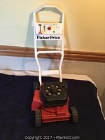 Full view of the vintage Fisher Price lawn mower toy showing the red body, black wheels, and white handle with control panel label.