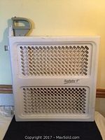 Front view of the white plastic Safety 1st baby gate with a rectangular grid pattern and gray locking mechanism.