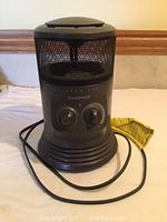 Photo of Honeywell surround heater showing its front with control knobs, mesh heating area, and attached power cord.