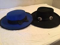 Two wool ladies dress hats pictured: one blue with black bow, one black Southwest-style hat with silver conchos.