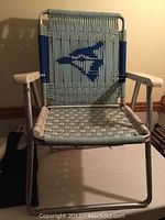 Front view of vintage Toronto Blue Jays folding chair showing metal frame, woven seat and back with logo, and plastic armrests.
