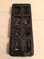 Plastic tray containing 5 metal figurine game pieces from the Star Wars Monopoly game, with various colored bases and character poses.