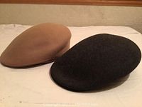 Photo of tan and dark navy wool newsboy hats side by side showing shape and color.