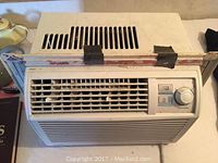 White Danby window air conditioner with visible control dial and buttons, and accordion side panels.