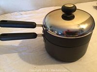 Photo of Circulon 8-inch diameter black steamer pot with long handle, auxiliary handle, and stainless steel lid with knob.