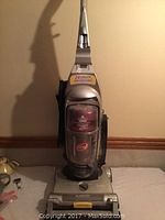 Front view of Bissell Powergroom upright vacuum cleaner showing clear dust container and handle