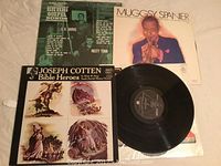 Four vinyl records displayed: Pink Floyd, Joseph Cotton, Muggsy Spanier, and Bluegrass Gospel Songs. Records and covers show age-appropriate wear. Muggsy Spanier record partially pulled out.