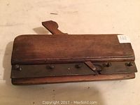 Antique J. Colton wooden hand plane lying flat on a surface, showing the top side with adjustment screws and the metal blade.
